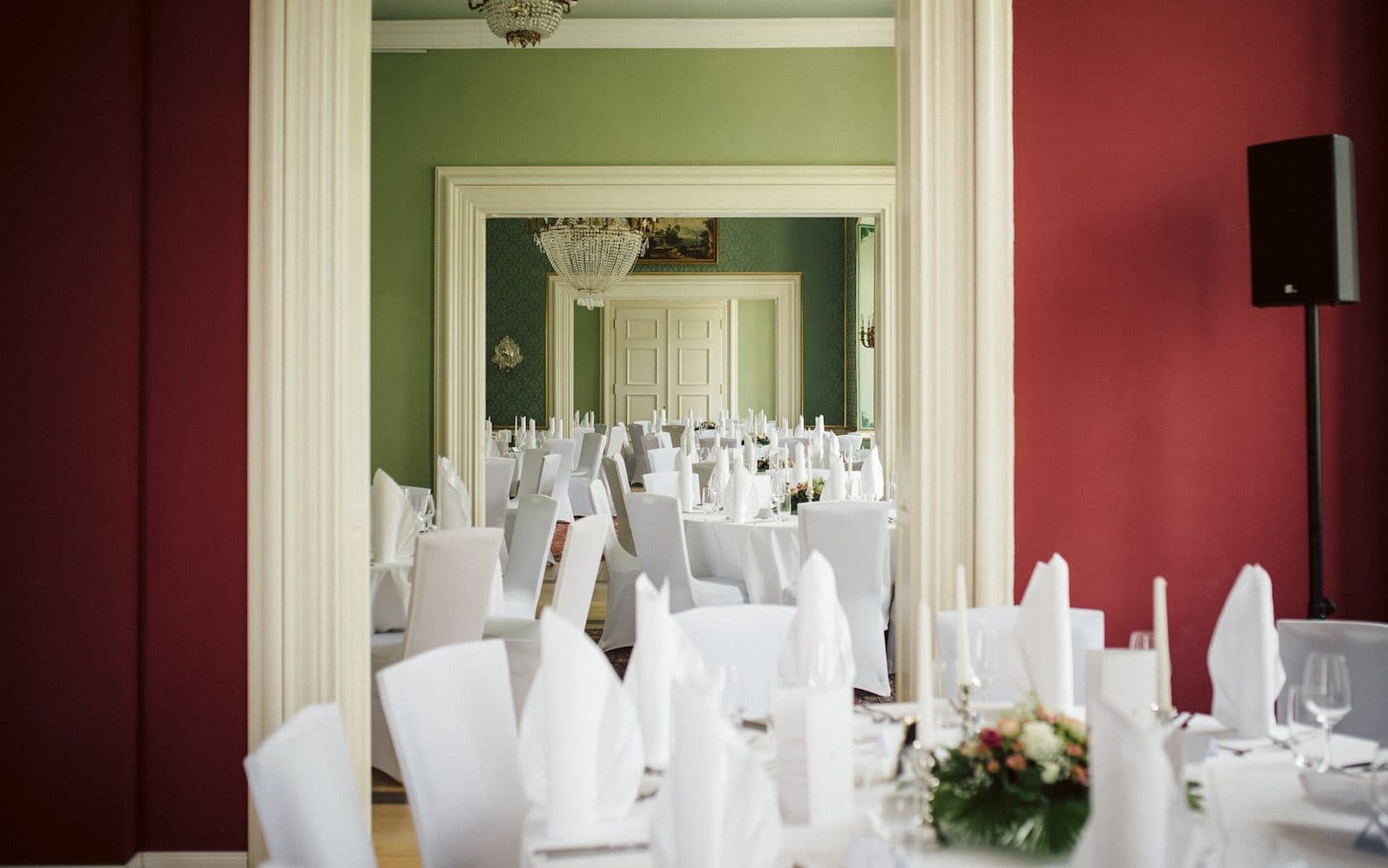 weiss gedeckte und geschmückte Hochzeitstische im roten Salon.