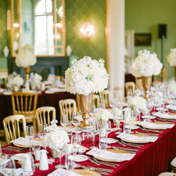 gedeckter hochzeitstisch im vintage stil mit decke aus rotem samt im schloss.