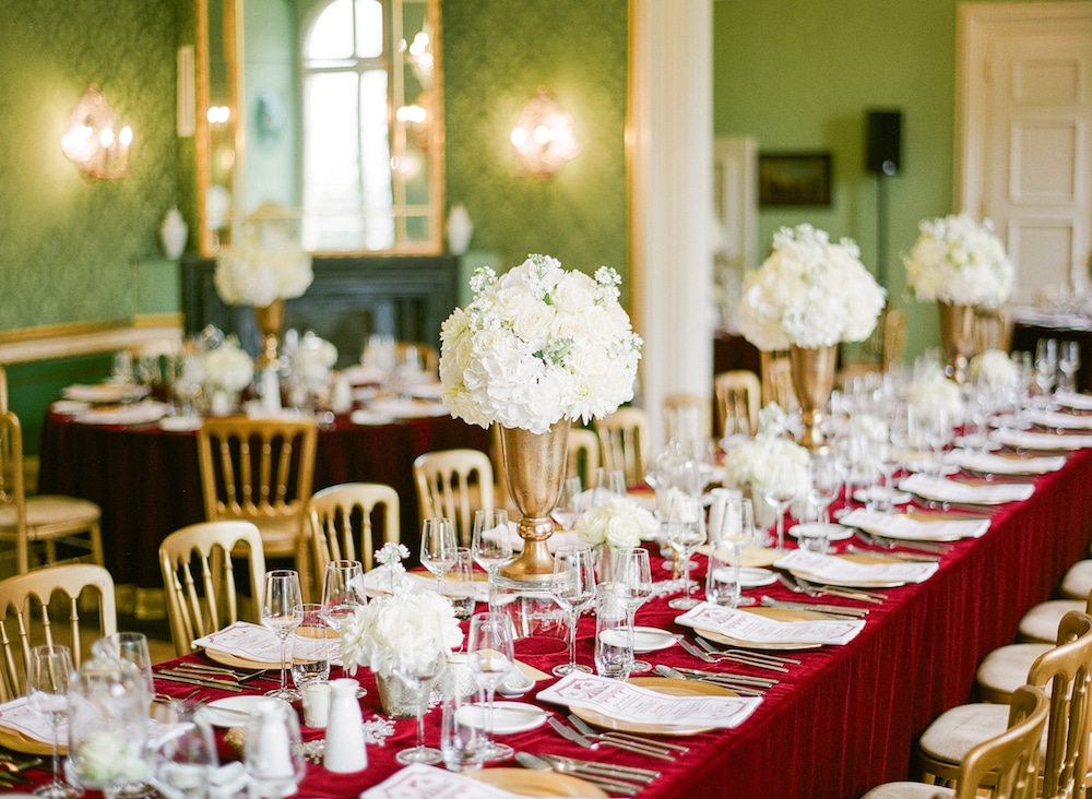 gedeckter hochzeitstisch im vintage stil mit decke aus rotem samt im schloss.