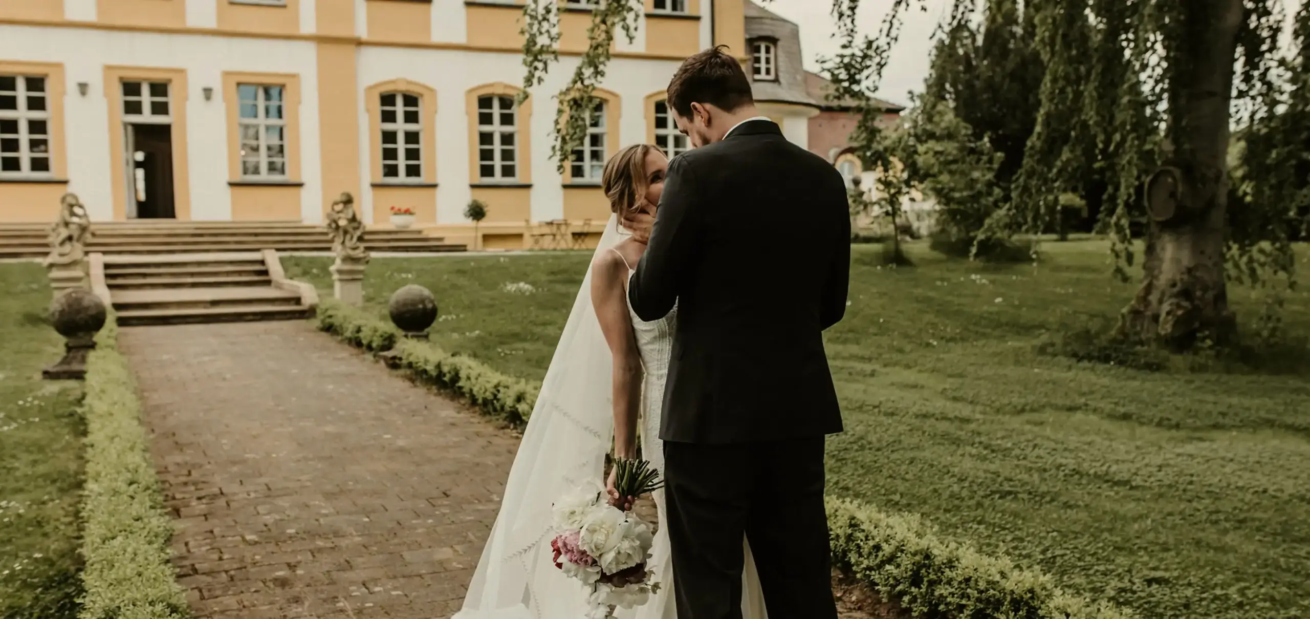 Aufmacher Hochzeitslocation Küssendes Paar vor dem Schloss Aufmacher Hochzeitslocation Küssendes Paar vor dem Schloss